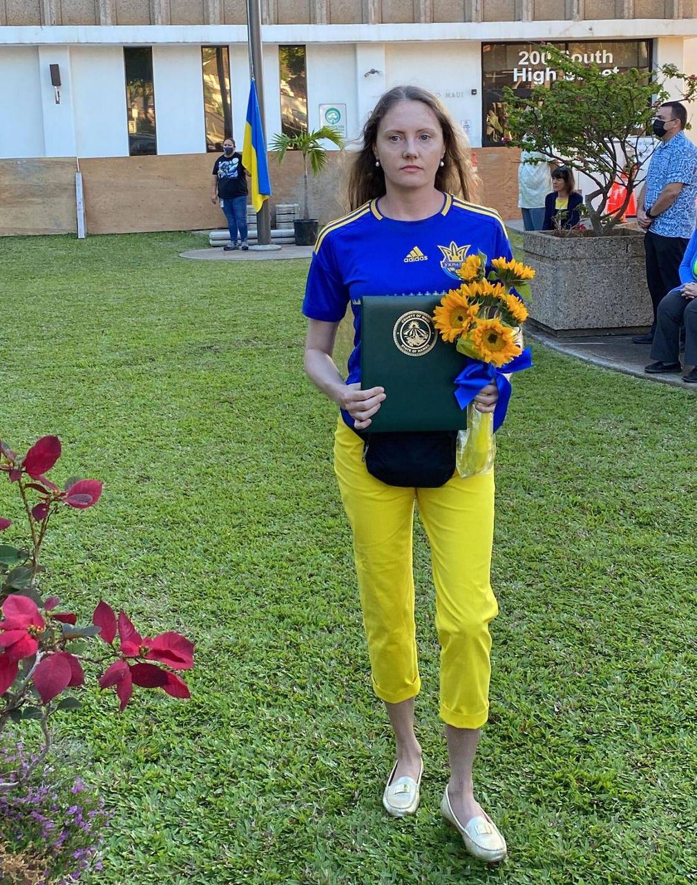 Yuliya LaBrosse holds the mayor’s proclamation on Ukraine Solidarity Day. Her Ukrainian flag is seen in the background. (Credit: Martina Hromadkova)