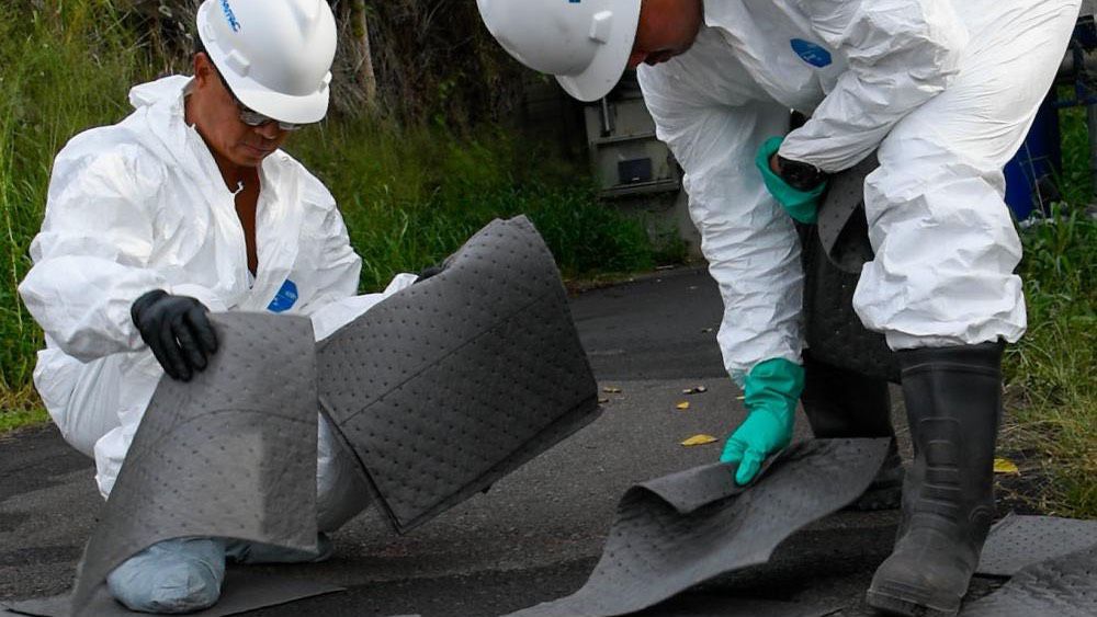 Two Naval Facilities Engineering System Command contractors place absorbent mats on an aqueous film-forming foam spill at the Red Hill Bulk Fuel Storage Facility. (Photo courtesy of U.S. Navy)