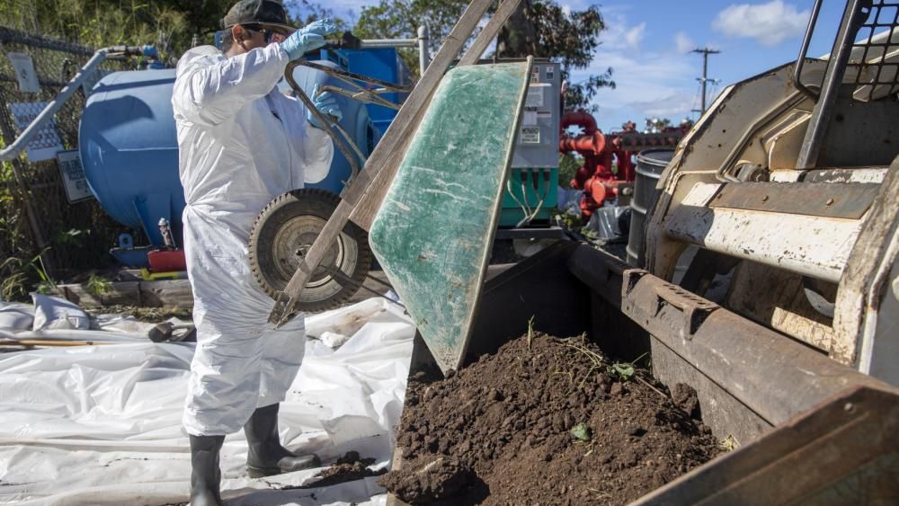 A Navy employee empties a wheelbarrow of contaminated soil into a tractor as part of a hazard material spill recovery operation at the Red Hill Bulk Storage Facility. (Photo courtesy of U.S. Navy)