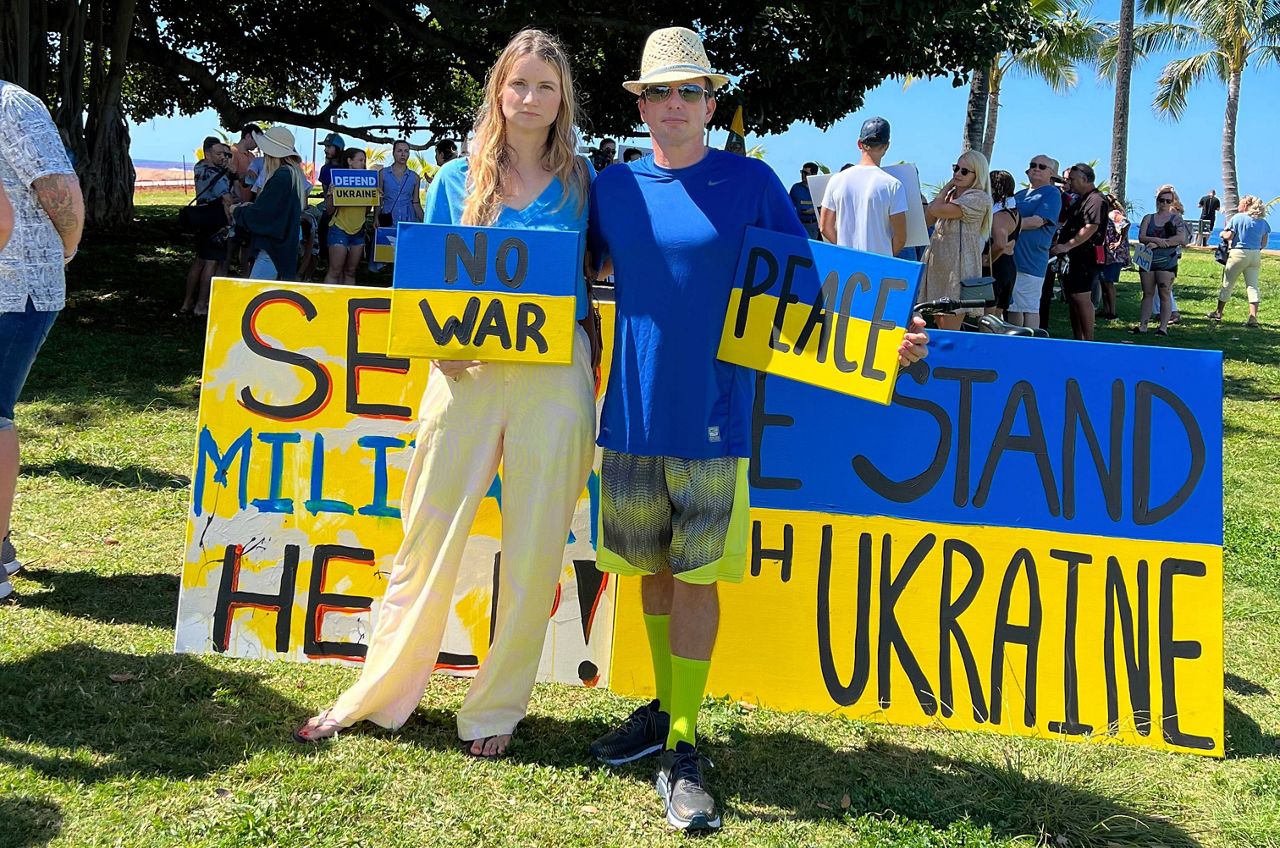 Olga Sousa stands with painted signs at a rally in support of Ukraine at Ala Moana Beach Park. (Credit: Olga Sousa)