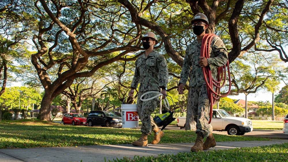 Two military members walk toward a Joint Base Pearl Harbor-Hickam resident’s home to conduct a field team home visit. (Credit: U.S. Navy)