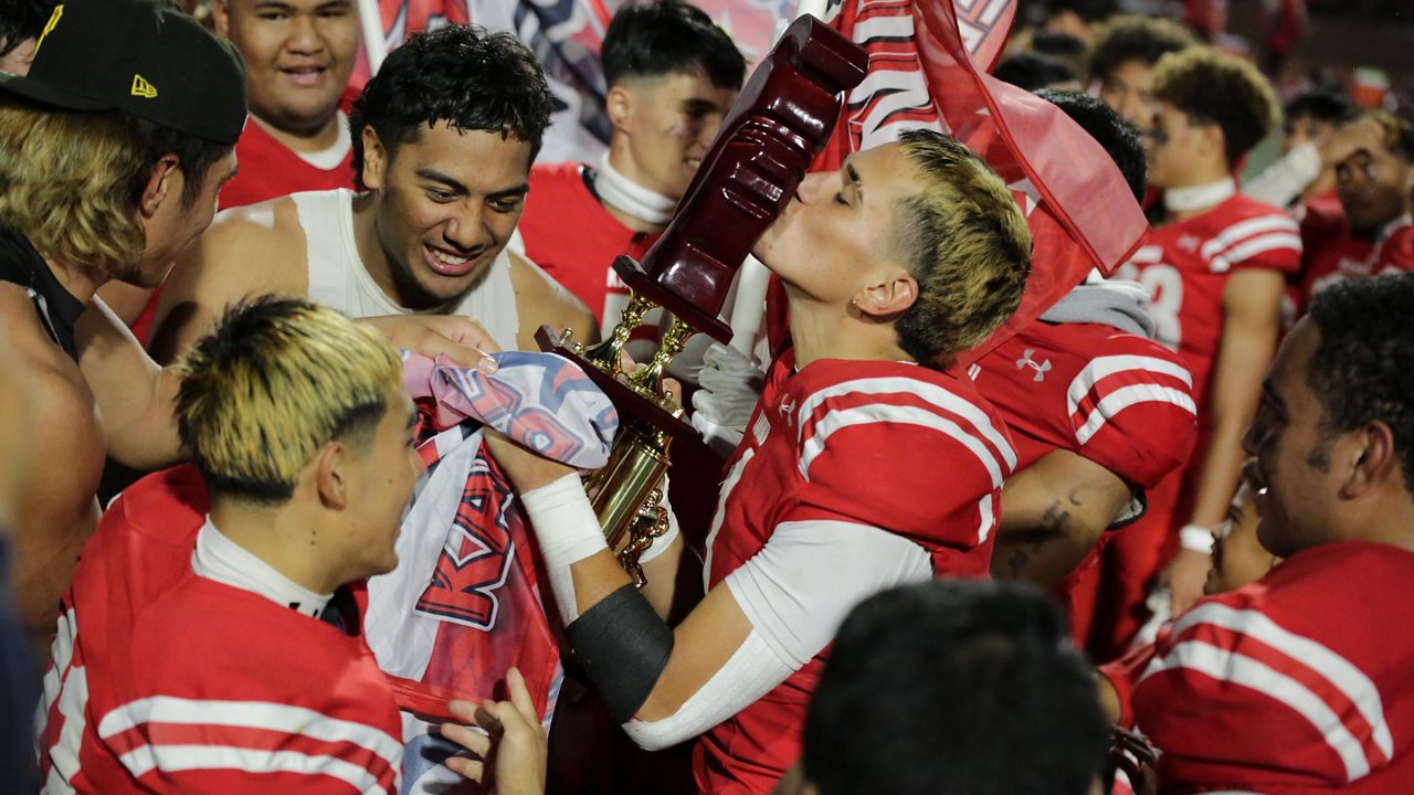 Kahuku quarterback Waika Crawford kissed the HHSAA Open Division koa trophy after the Red Raiders won their second straight championship.