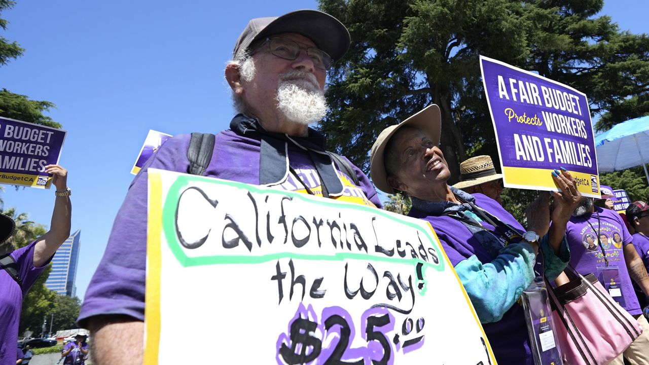  Retirees Ron Martin, left, and Willie Mae Hampton, right, join other supporters of the Service Employees International Union at a rally against proposed budget cuts to state provided social safety net programs, in Sacramento, Calif., Tuesday, June 11, 2024. On Saturday, June 22, 2024, California Gov. Gavin Newsom and the Democrats who control the state Legislature agreed to delay an upcoming minimum wage increase for health care workers to help balance the budget. (AP Photo/Rich Pedroncelli, File)