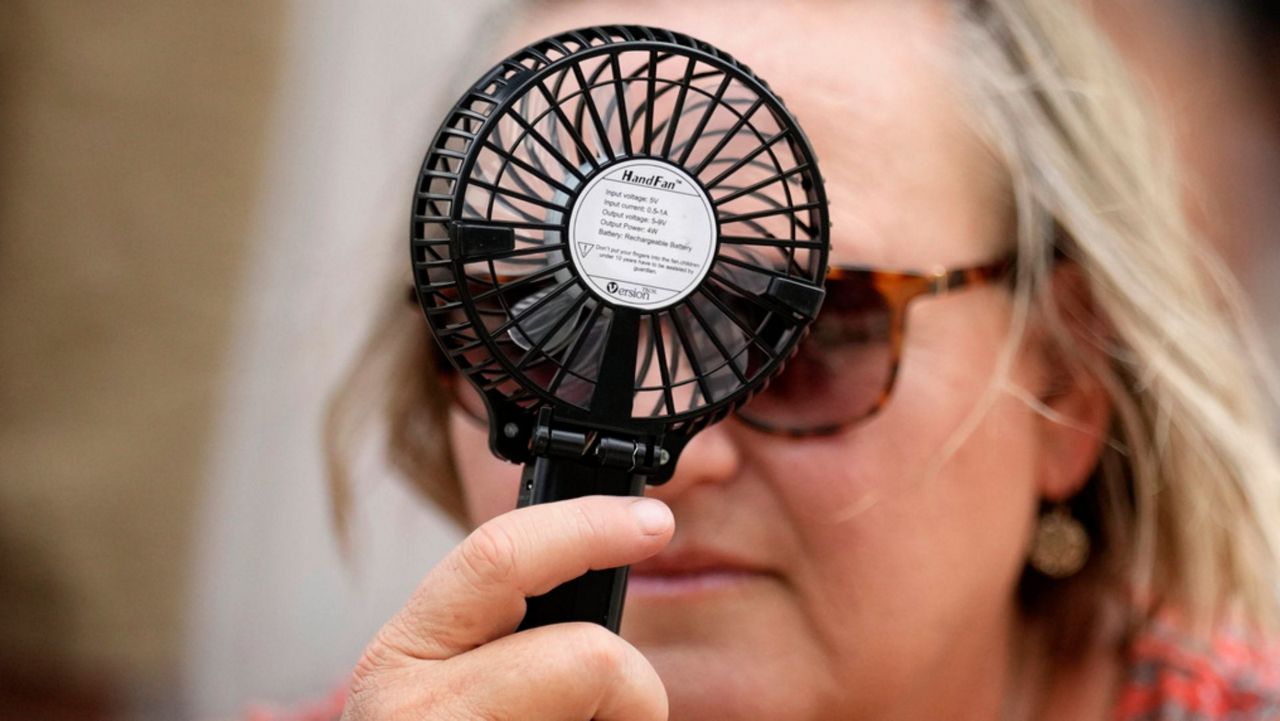 Woman with fan cooling her off