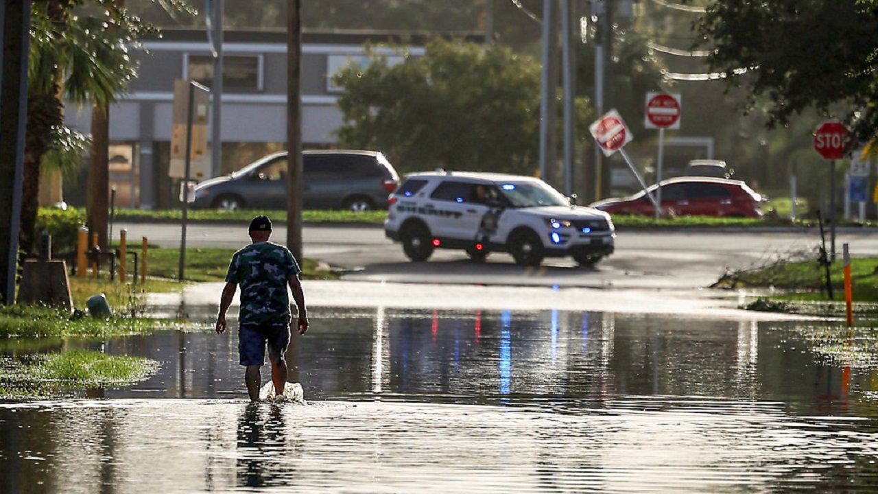 A man walks out of a street with water flooded from Hurricane Helene Friday, Sept. 27, 2024, in New Port Richey, Fla. (AP Photo/Mike Carlson)