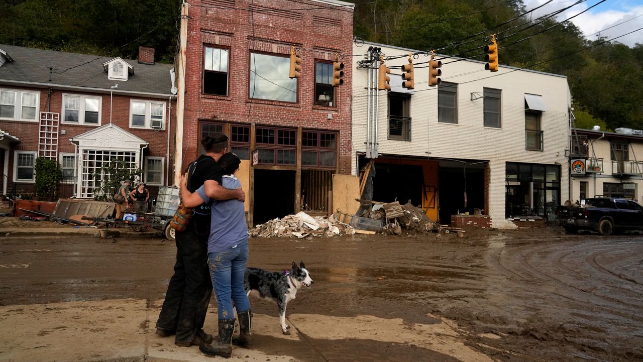 Resident Anne Schneider, right, hugs her friend Eddy Sampson as they survey damage left in the wake of Hurricane Helene, Tuesday, Oct. 1, 2024, in Marshall, N.C. (AP Photo/Jeff Roberson)