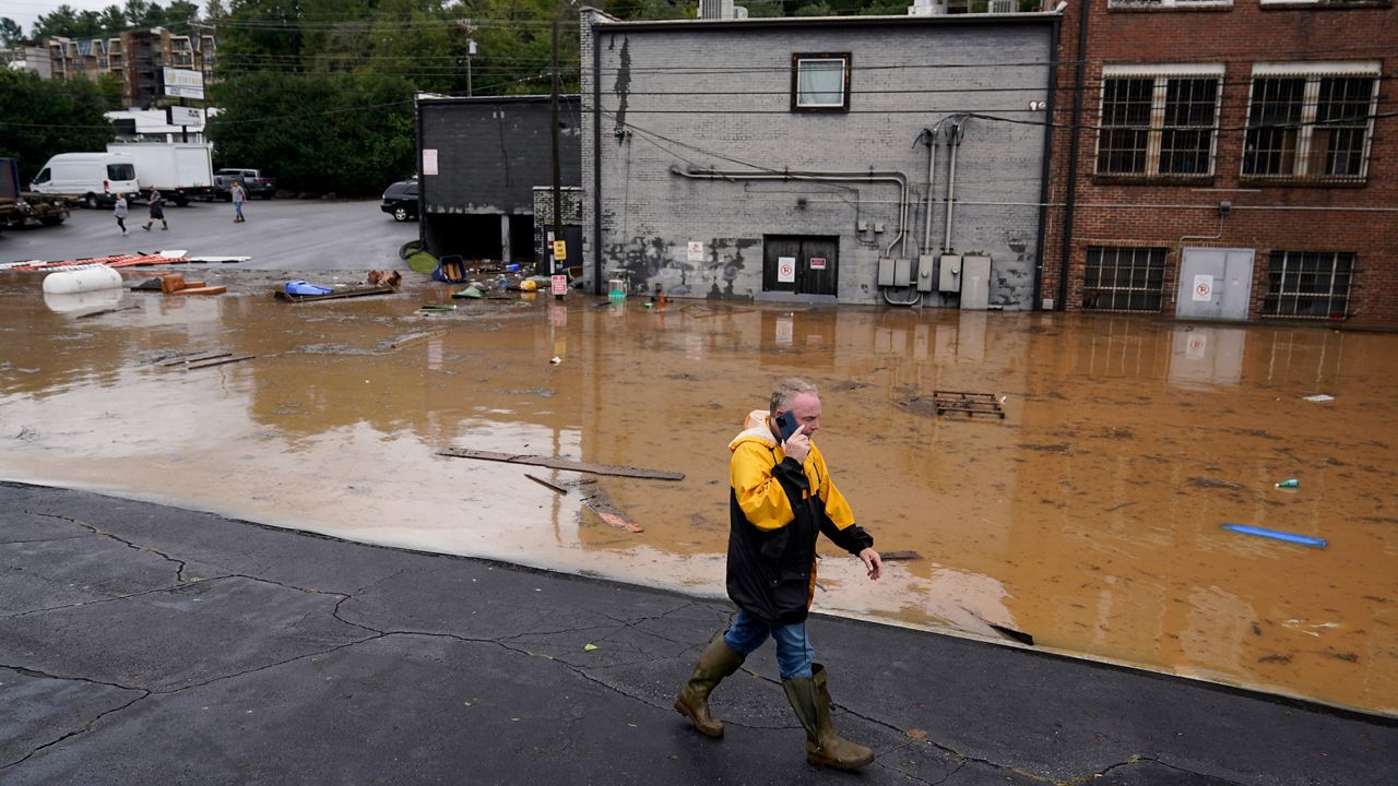 A man walks near a flooded area following Hurricane Helene on Sept. 27, 2024, in Asheville, N.C. (AP Photo/Erik Verduzco)