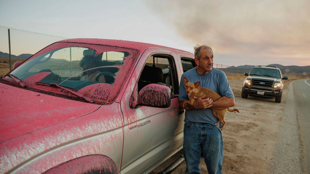 Rick Fitzpatrick holds a dog after evacuating from the Fairview Fire Monday near Hemet, Calif. (AP Photo/Ethan Swope)