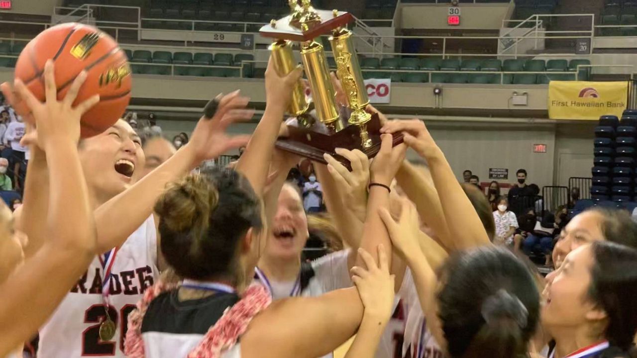 Iolani players piled around the HHSAA Division I basketball championship trophy at the Neal Blaisdell Center after beating Konawaena.