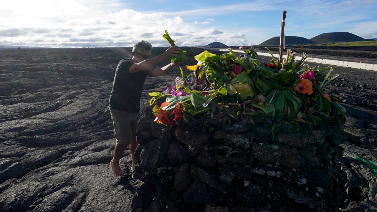 Allen Mozo, of Haleiwa, leaves an offering at an alter below the Mauna Loa volcano as it erupts Thursday, Dec. 1, 2022, near Hilo, Hawaii. Glowing lava from the world's largest volcano is a sight to behold, but for many Native Hawaiians, Mauna Loa's eruption is a time to pray, make offerings and honor both the natural and spiritual worlds. (AP Photo/Gregory Bull)