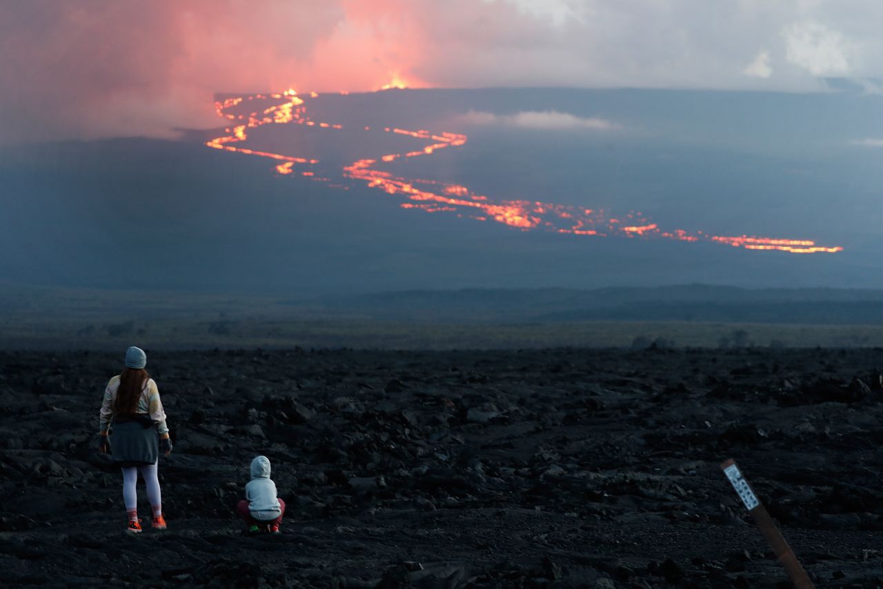 Spectators watch the lava flow down the mountain from the Mauna Loa eruption, Tuesday, Nov. 29, 2022, near Hilo, Hawaii. (AP Photo/Marco Garcia)