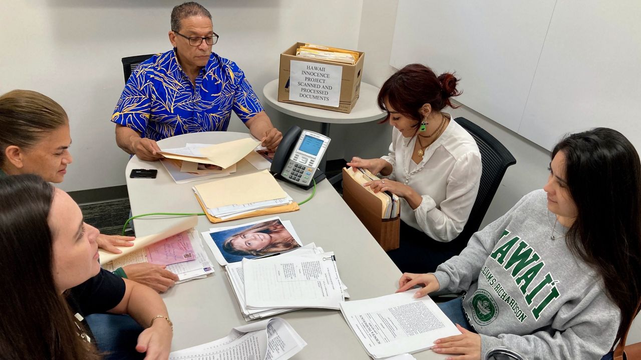 Hawaii Innocence Project co-director Kenneth Lawson, background center, and law students go over files and photos related to the 1991 murder of Dana Ireland in Honolulu on Tuesday, Jan. 17, 2023. (AP Photo/Jennifer Sinco Kelleher)