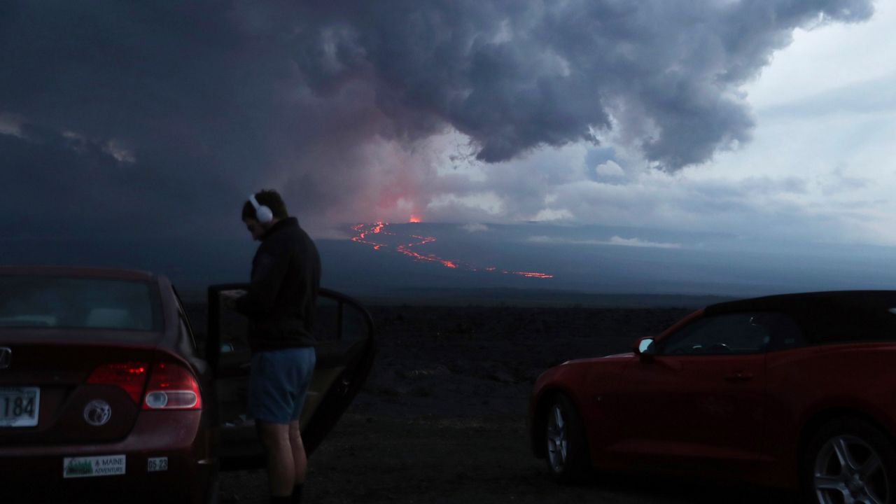 Spectators watch the lava flow down the mountain from the Mauna Loa eruption, Tuesday, Nov. 29, 2022, near Hilo, Hawaii. (AP Photo/Marco Garcia)