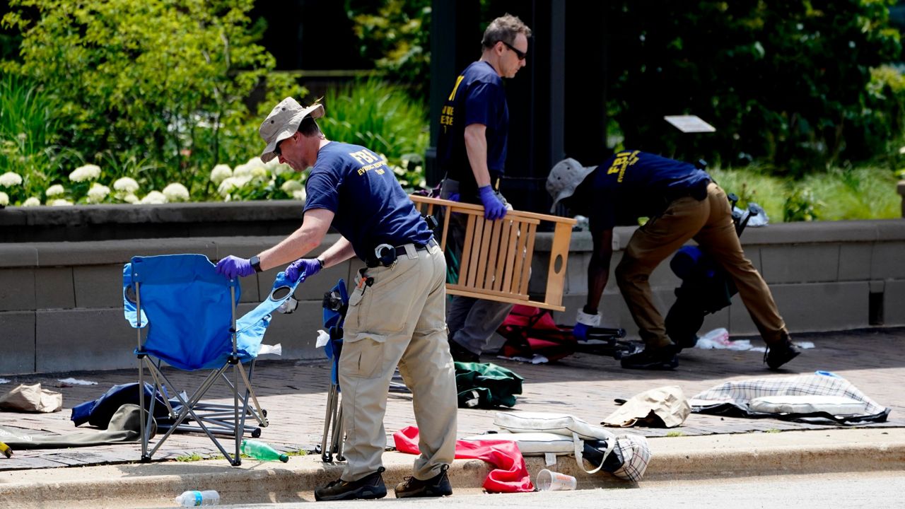 Members of the FBI's evidence response team remove personal belongings Tuesday, one day after a mass shooting in downtown Highland Park, Ill. (AP Photo/Charles Rex Arbogast)