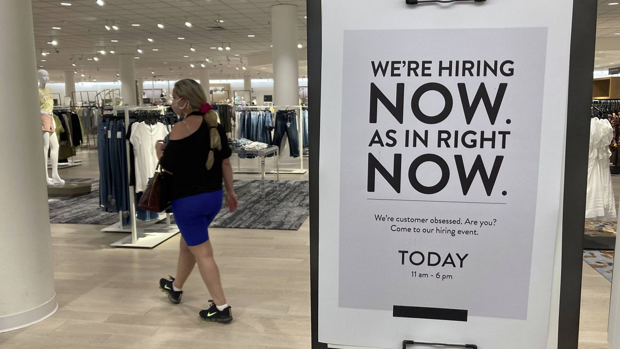 A customer walks behind a sign at a Nordstrom store seeking employees on May 21 in Coral Gables, Fla. (AP Photo/Marta Lavandier)