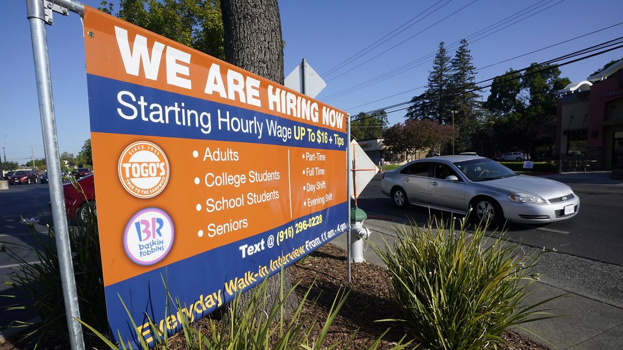 A car passes a hiring banner in Sacramento, Calif., on Friday.