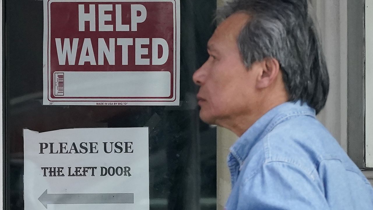 A pedestrian walks on April 18 past a help-wanted sign posted on the door of a restaurant in San Francisco. (AP Photo/Jeff Chiu)