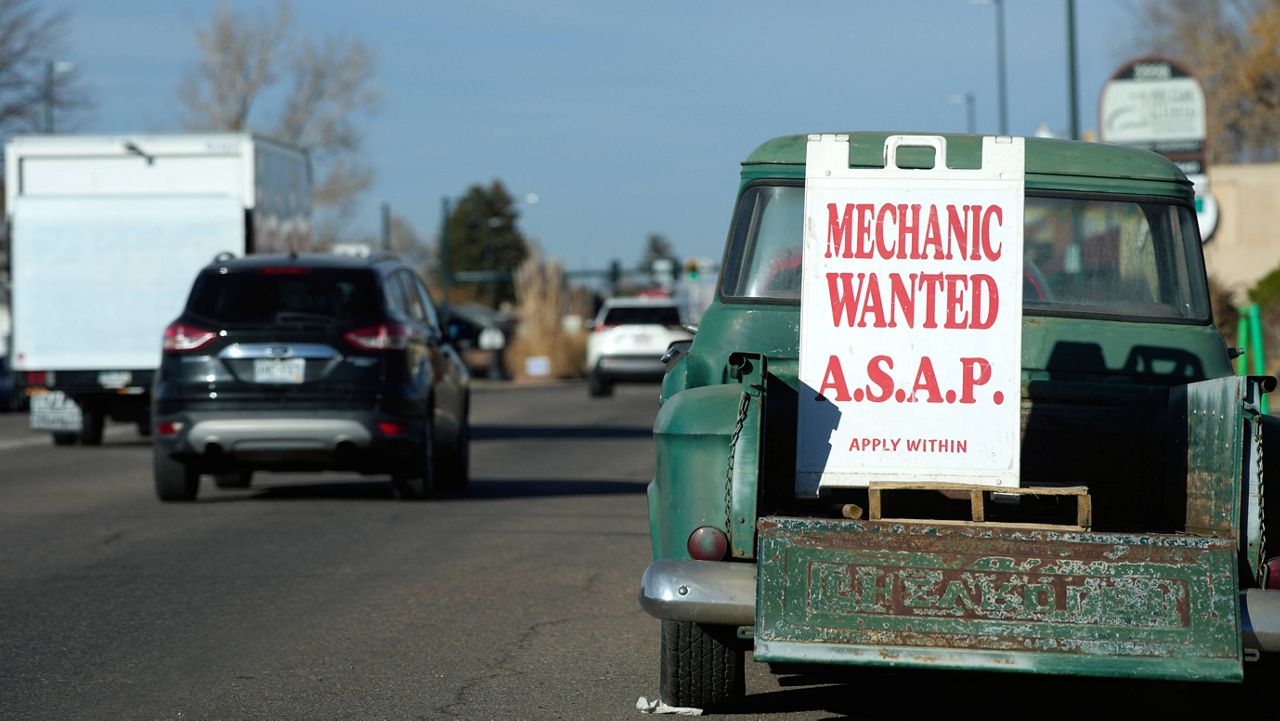 A sign advertising the need for a mechanic stands in the back of an aged Chevrolet pickup truck Tuesday in Englewood, Colo. (AP Photo/David Zalubowski)