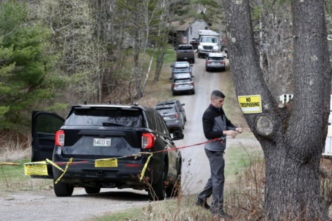 A police officer hangs a rope blocking off the driveway to 1459 Augusta Road in Bowdoin the day after four bodies were discovered at the home. (Ben McCanna/Portland Press Herald)