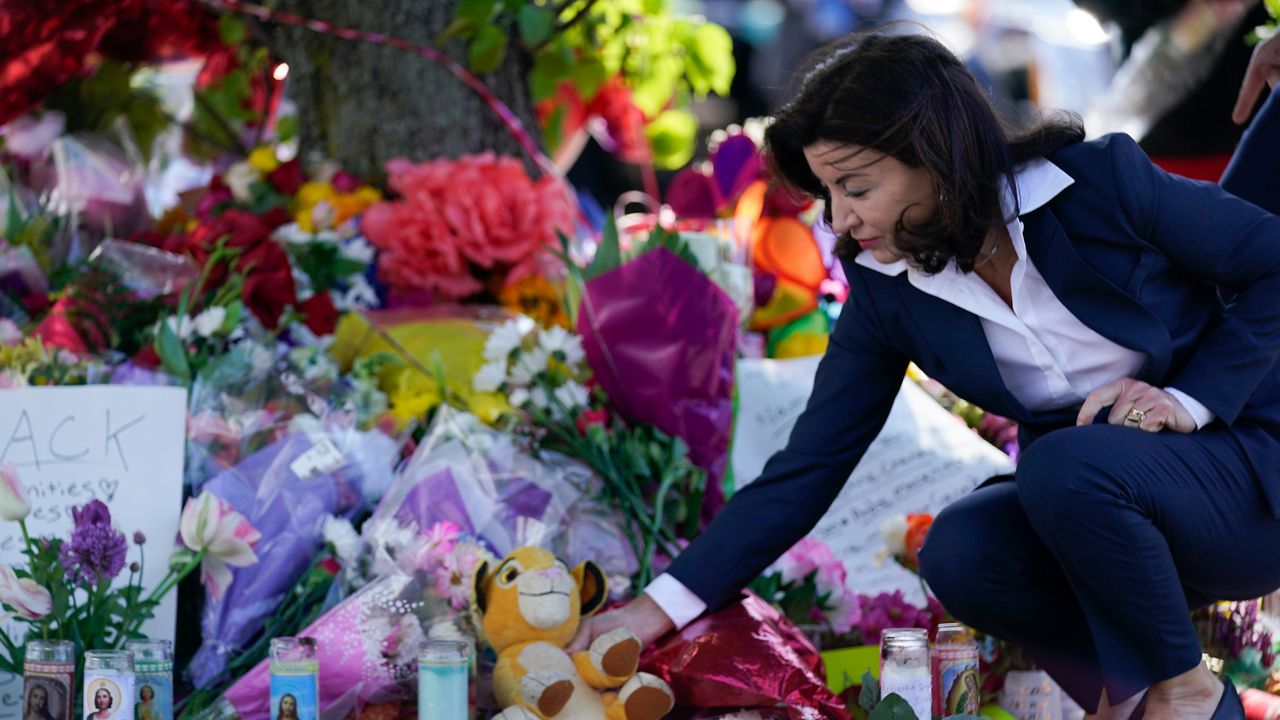 New York Gov. Kathy Hochul looks at a memorial at the scene of a shooting at a supermarket as she pays respects to the victims of Saturday's shooting in Buffalo, N.Y., Tuesday, May 17, 2022. (AP Photo/Andrew Harnik)