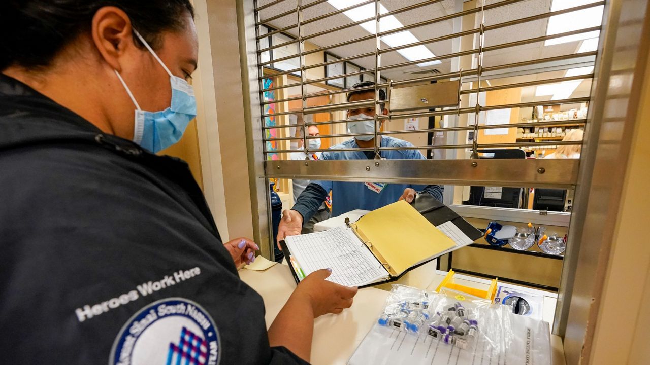 A nurse picks up vials of the COVID-19 vaccine at Mount Sinai South Nassau for inoculating homebound seniors, May 20, 2021. (AP Photo/Mary Altaffer)