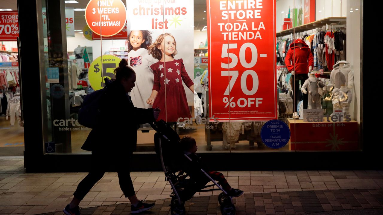 A shopper walks in front of Christmas sales signs Monday, Dec. 16, 2019, in Santa Clarita, Calif. (AP Photo/Marcio Jose Sanchez)