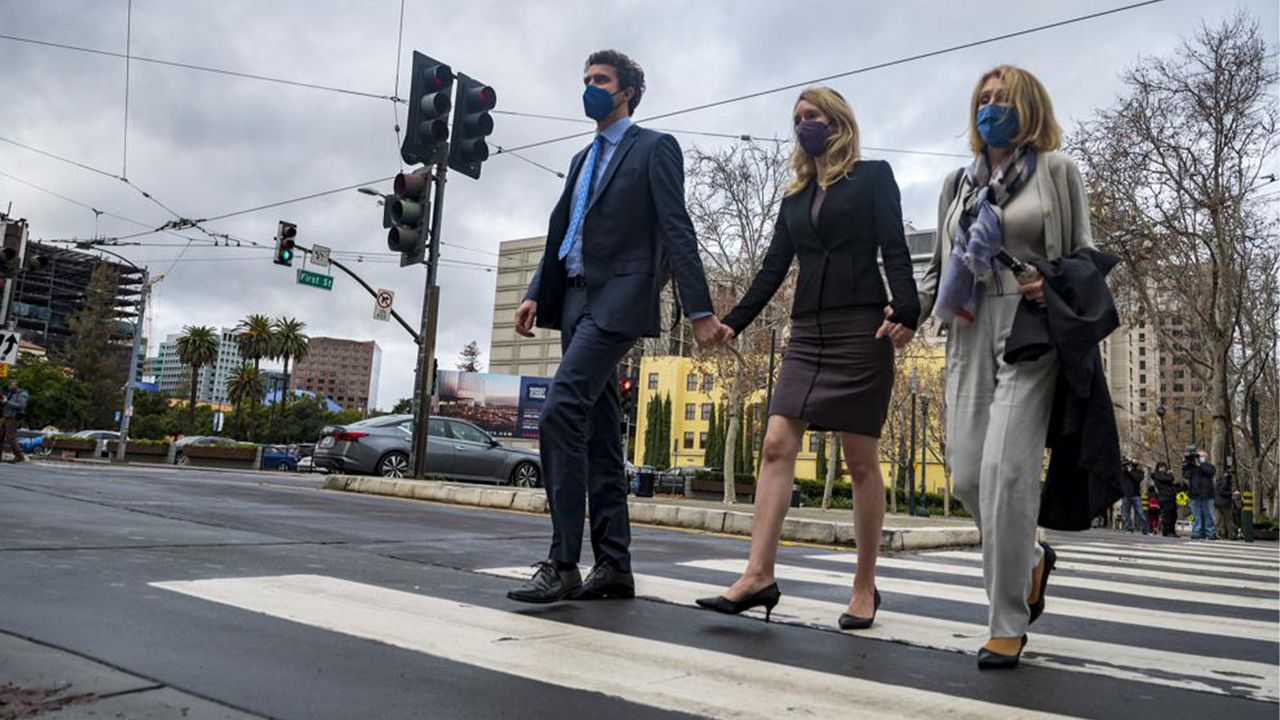 Former Theranos CEO Elizabeth Holmes, center, with her partner, Billy Evans, left, and mother, Noel Holmes, right, leaves federal court in San Jose, Calif., Thursday, Dec. 23, 2021. The jury began their third day of deliberations in her fraud and conspiracy trial on Thursday. (AP Photo/Nic Coury)