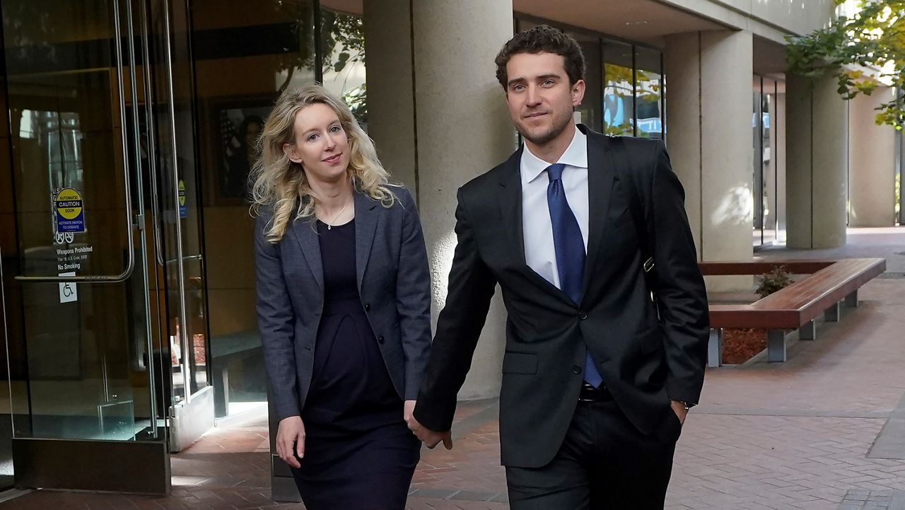 Former Theranos CEO Elizabeth Holmes, left, walks with her partner, Billy Evans, after leaving federal court in San Jose, Calif., Monday, Oct. 17, 2022. (AP Photo/Jeff Chiu)