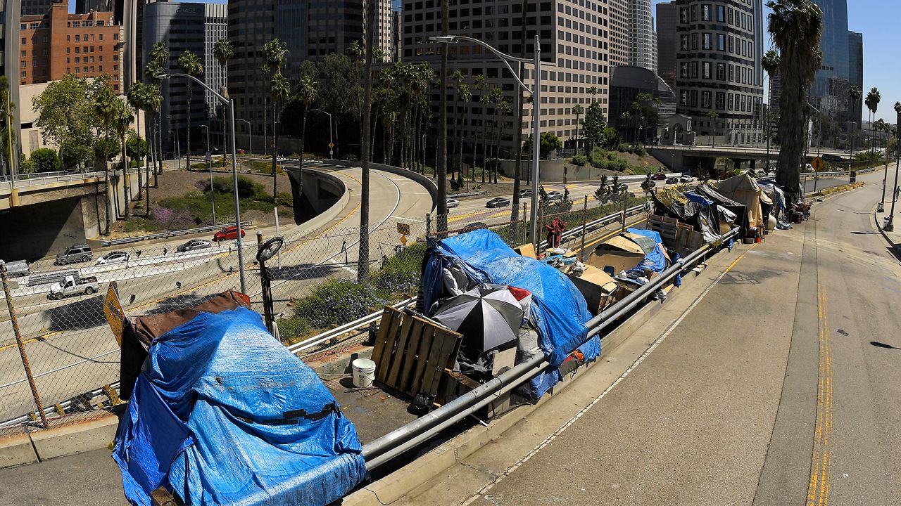 This May 21, 2020, file photo shows a homeless encampment on Beaudry Avenue as traffic moves along Interstate 110 in downtown Los Angeles. Los Angeles is again considering a proposal to greatly restrict where homeless people may camp in public places around Los Angeles — rules that opponents say would criminalize homelessness. The City Council on Wednesday, Oct. 28, 2020. (AP Photo/Mark J. Terrill, File)