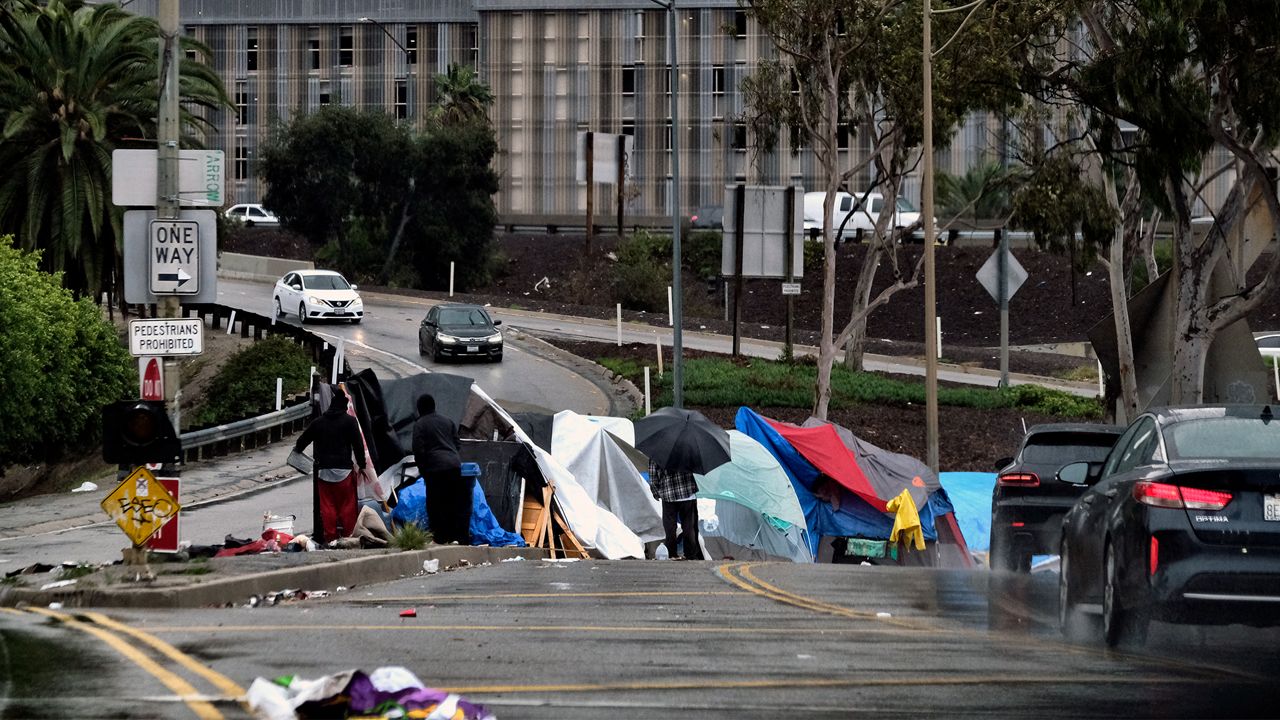 In this Jan. 14, 2019, file photo homeless shelter from a storm passing over downtown Los Angeles at their encampment along an offramp to the 110 freeway. (AP Photo/Richard Vogel, File)