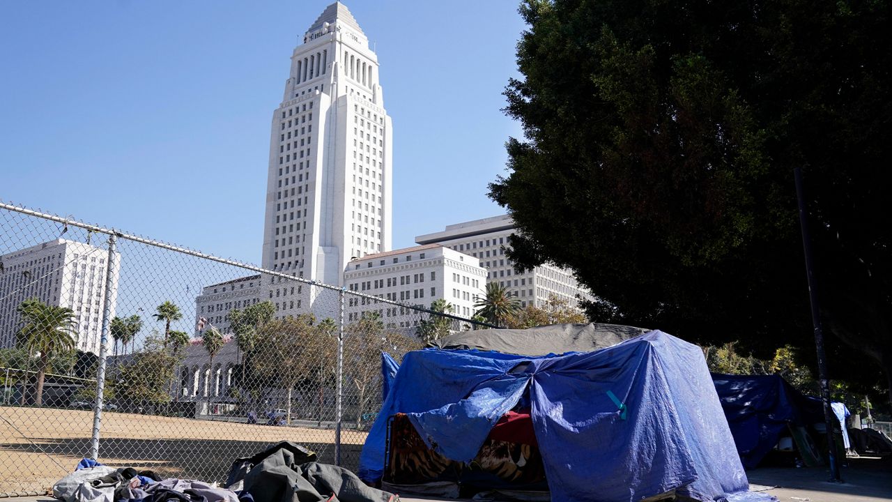 A homeless person's tent stands just outside Grand Park with Los Angeles City Hall in the background, Wednesday, Oct. 28, 2020, in Los Angeles. (AP Photo/Chris Pizzello)