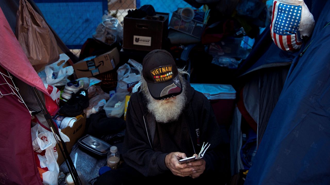 Theodore Neubauer, a 78-year-old Vietnam War veteran, who is homeless, looks at his smartphone while passing time in his tent Friday, Dec. 1, 2017, in Los Angeles. 