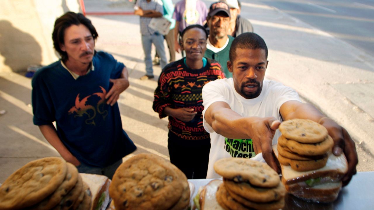 People experiencing homelessness line up to receive food. (AP)