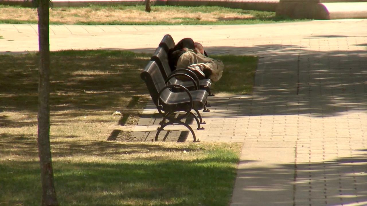 homeless youth lying on a park bench
