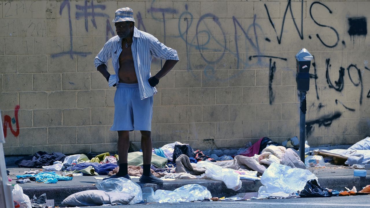 A homeless man stands amongst a trash lined street in downtown Los Angeles on Thursday, May 30, 2019. (AP Photo/Richard Vogel)