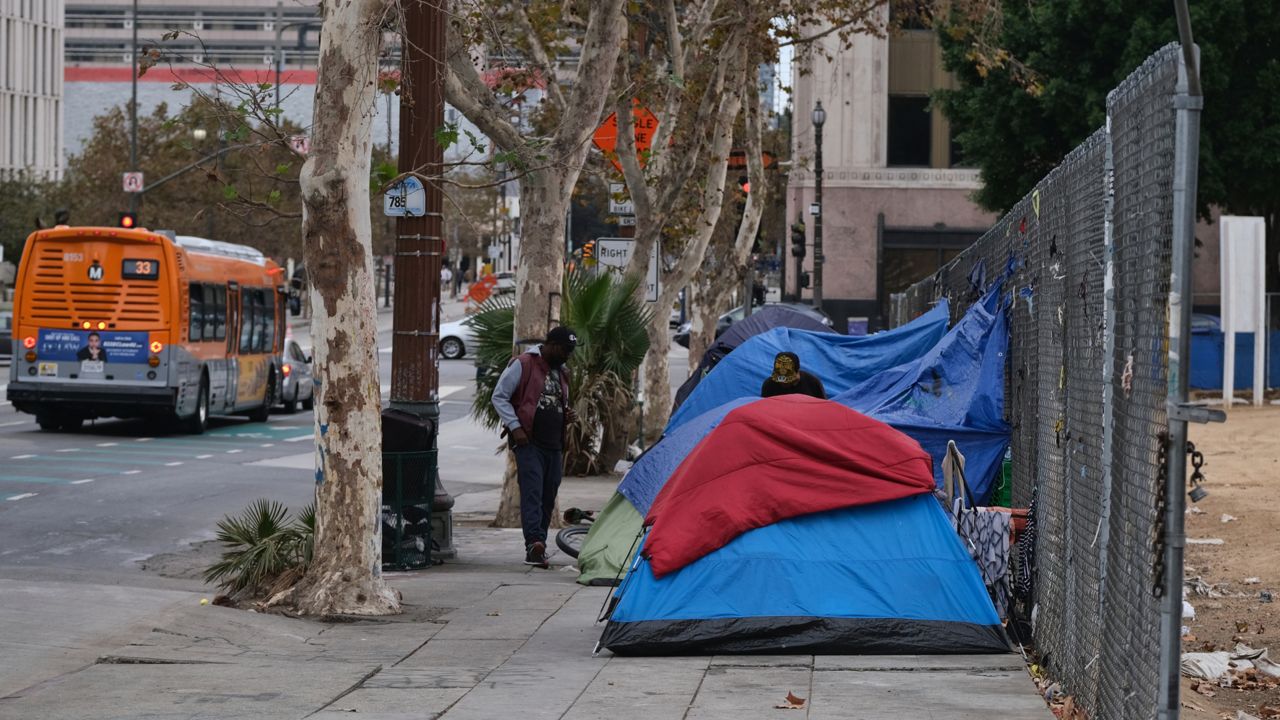 Homeless men stand by their tents along the street across from Los Angeles City Hall, on Saturday, Oct. 22, 2022. (AP Photo/Richard Vogel)