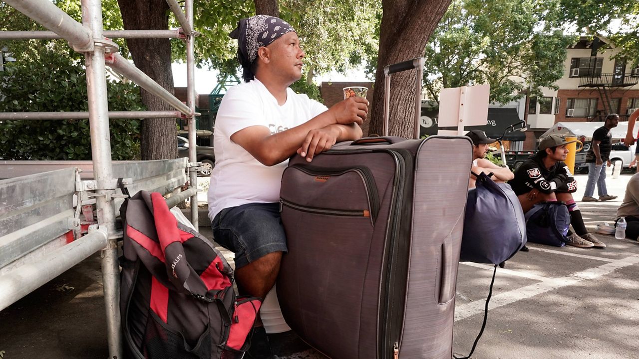 Eric Santos uses a suitcase that he keeps all of his possessions in as a table while having a cup of coffee at ShowUp Sac, a nonprofit that provides food, clothing and showers to people experiencing homelessness in Sacramento, Calif., Tuesday, Aug. 9, 2022. (AP Photo/Rich Pedroncelli)