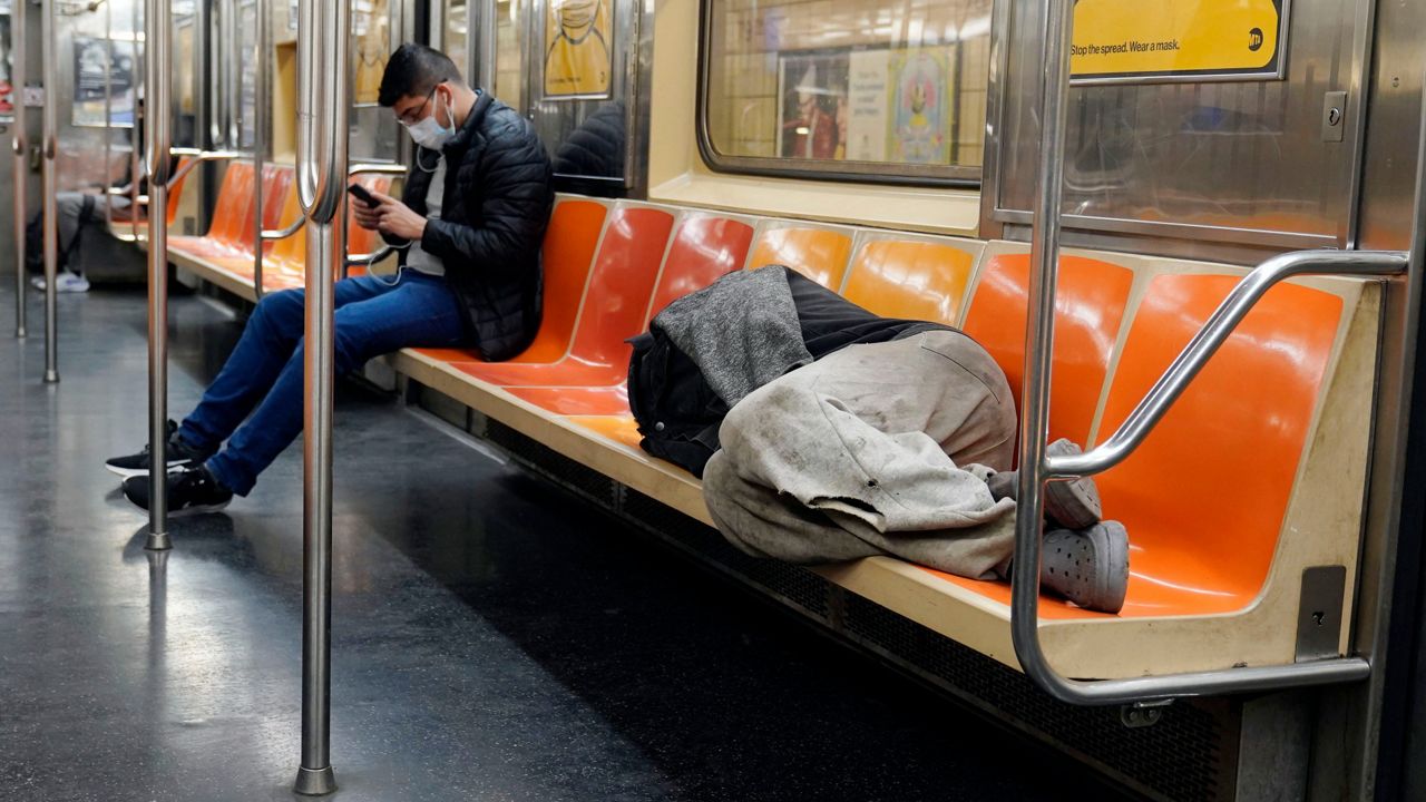 A man sleeps on subway train seats, in New York, on April 14, 2021.
