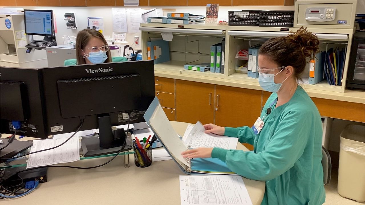 Hospital staff work at a desk. (Spectrum News 1/File)