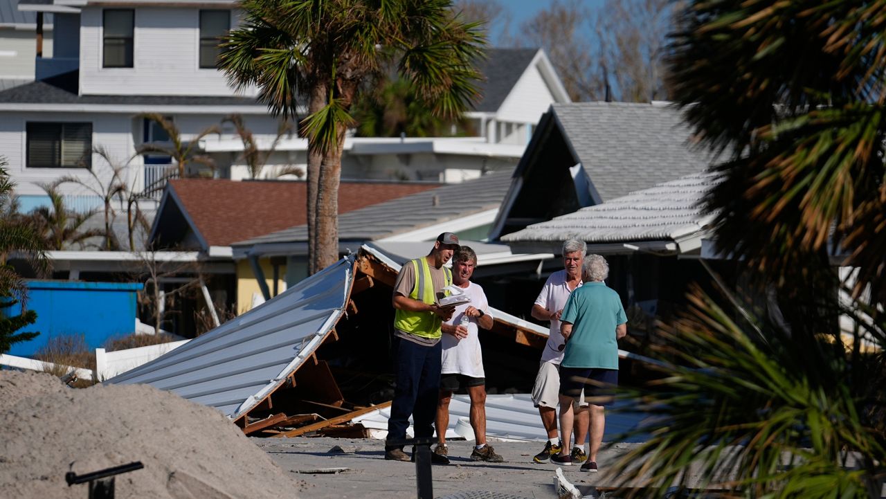 FILE - Property owners speak with an official as they process the damage to their homes and community following Hurricane Milton, on Manasota Key, in Englewood, Fla., Sunday, Oct. 13, 2024. (AP Photo/Rebecca Blackwell)