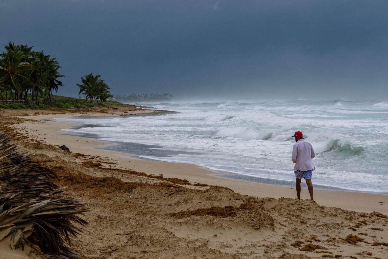 A man walks on the beach next to waves kicked up by Hurricane Fiona in Punta Cana, Dominican Republic, Monday, Sept. 19, 2022.