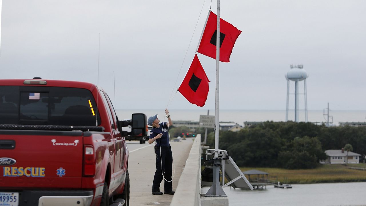 Chief Ann Graham, with the Isle of Palms Fire Department, raises two hurricane flags over the Isle of Palms Connector in preparation for Hurricane Matthew on Isle of Palms, S.C., Thursday, Oct. 6, 2016. (AP Photo/Mic Smith)