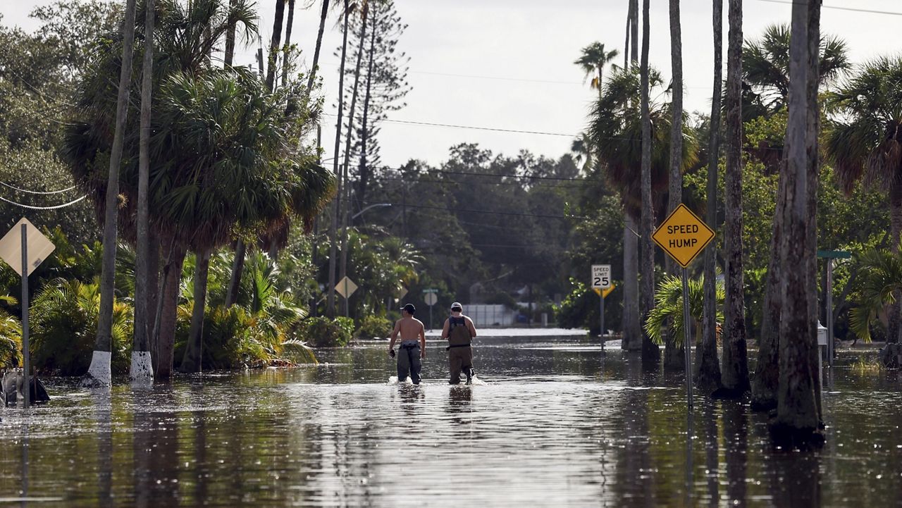 Men walk down a street flooded by Hurricane Helene in the Shore Acres neighborhood Sept. 27, 2024, in St. Petersburg, Fla. (AP Photo/Mike Carlson, File)