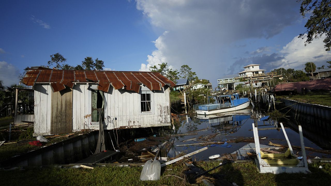 A cottage teeters over a canal, alongside the remnants of the family's destroyed business, Ed's Baithouse and Marina, in Horseshoe Beach, Fla., Thursday, Aug. 31, 2023.