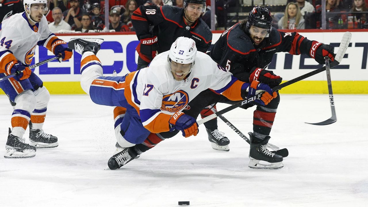 Carolina Hurricanes' Jalen Chatfield (5) battles with New York Islanders' Anders Lee (27) for the puck during the first period in Game 5 of an NHL hockey Stanley Cup first-round playoff series in Raleigh, N.C., Tuesday, April 30, 2024. (AP Photo/Karl B DeBlaker)