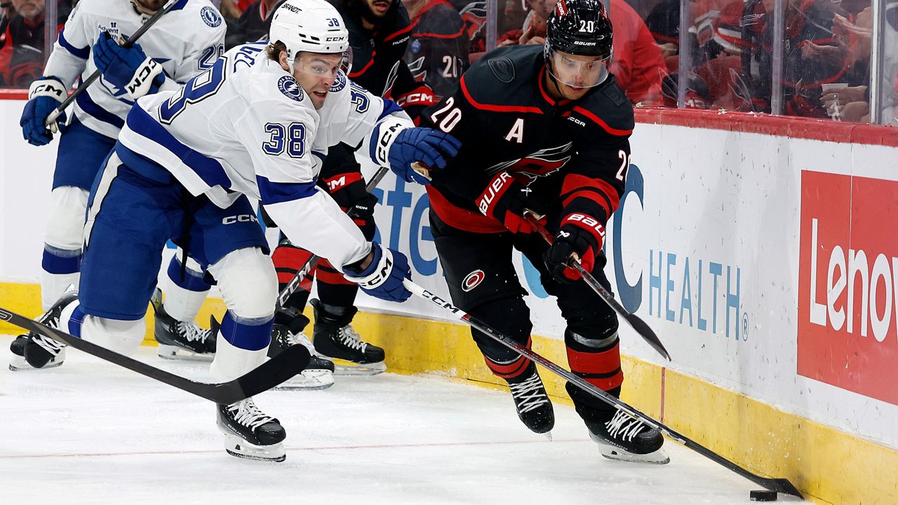 Carolina Hurricanes' Sebastian Aho (20) battles for the puck with Tampa Bay Lightning's Brandon Hagel (38) during the first period of an NHL hockey game in Raleigh, N.C., Friday, Oct. 11, 2024. (AP Photo/Karl B DeBlaker)