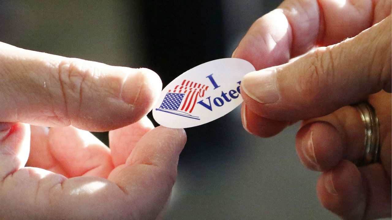 "I Voted" sticker passing between two hands in this file photos. (AP Photo/Rogelio V. Solis)