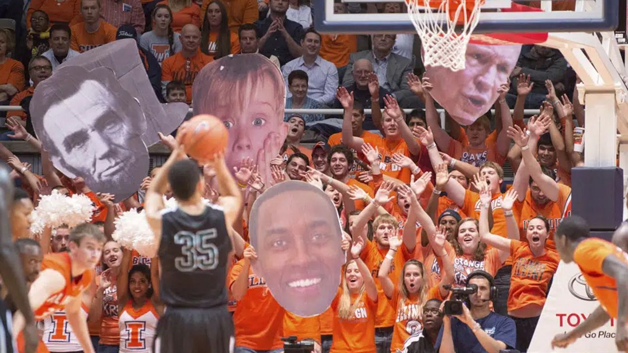 The Illinois Orange Krush student section uses large heads to heckle Chicago State's Clarke Rosenberg (35) as he tries for a foul shot during the second half of an NCAA college basketball game on Nov. 22, 2013, in Champaign, Ill. The Illinois student spirit group “Orange Krush” had its order for 200 tickets to the men's basketball game at Carver-Hawkeye Arena on Saturday, Feb. 4, 2023, canceled, after Iowa discovered the person who made the purchase falsely claimed the tickets were for a Boys and Girls Club. (AP Photo/Darrell Hoemann, File)