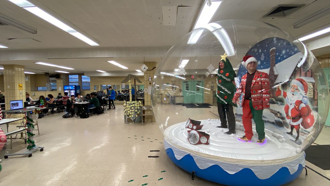 Staten Island Technical High School’s Mark Erlenwein encouraged holiday fun by blowing up an inflatable snow globe and getting inside it. (NY1/Jillian Jorgensen)