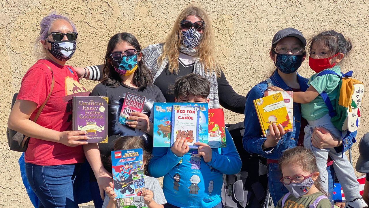 LAUSD teacher Dr. Claudia Cataldo stands with a family of book-lovers outside her late April bookmobile "pop-up." (David Mendez/Spectrum News)